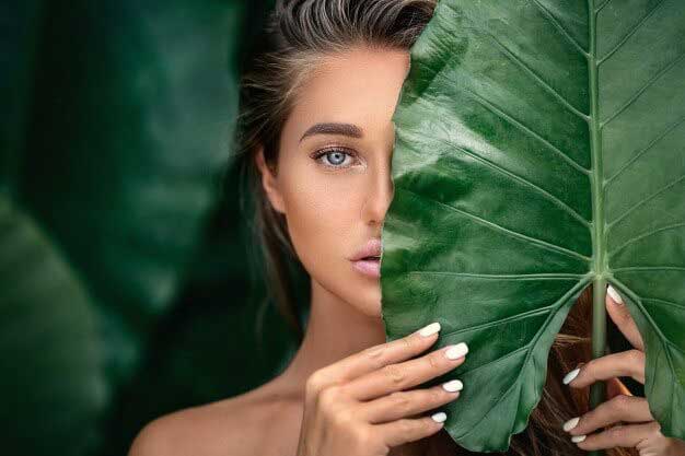 Woman looking through green leaves